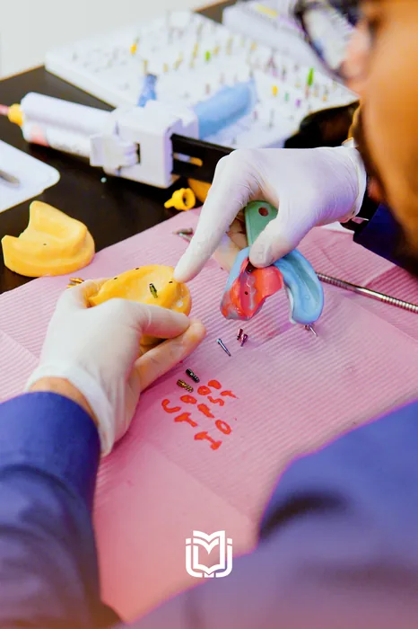 Gloved hands placing implant components into a training model