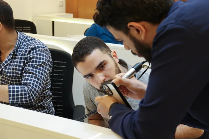 An instructor guiding a participant's handpiece during a drilling workshop