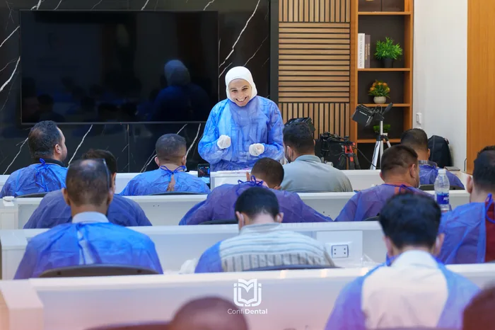 An instructor in surgical gown teaching a room of gowned participants